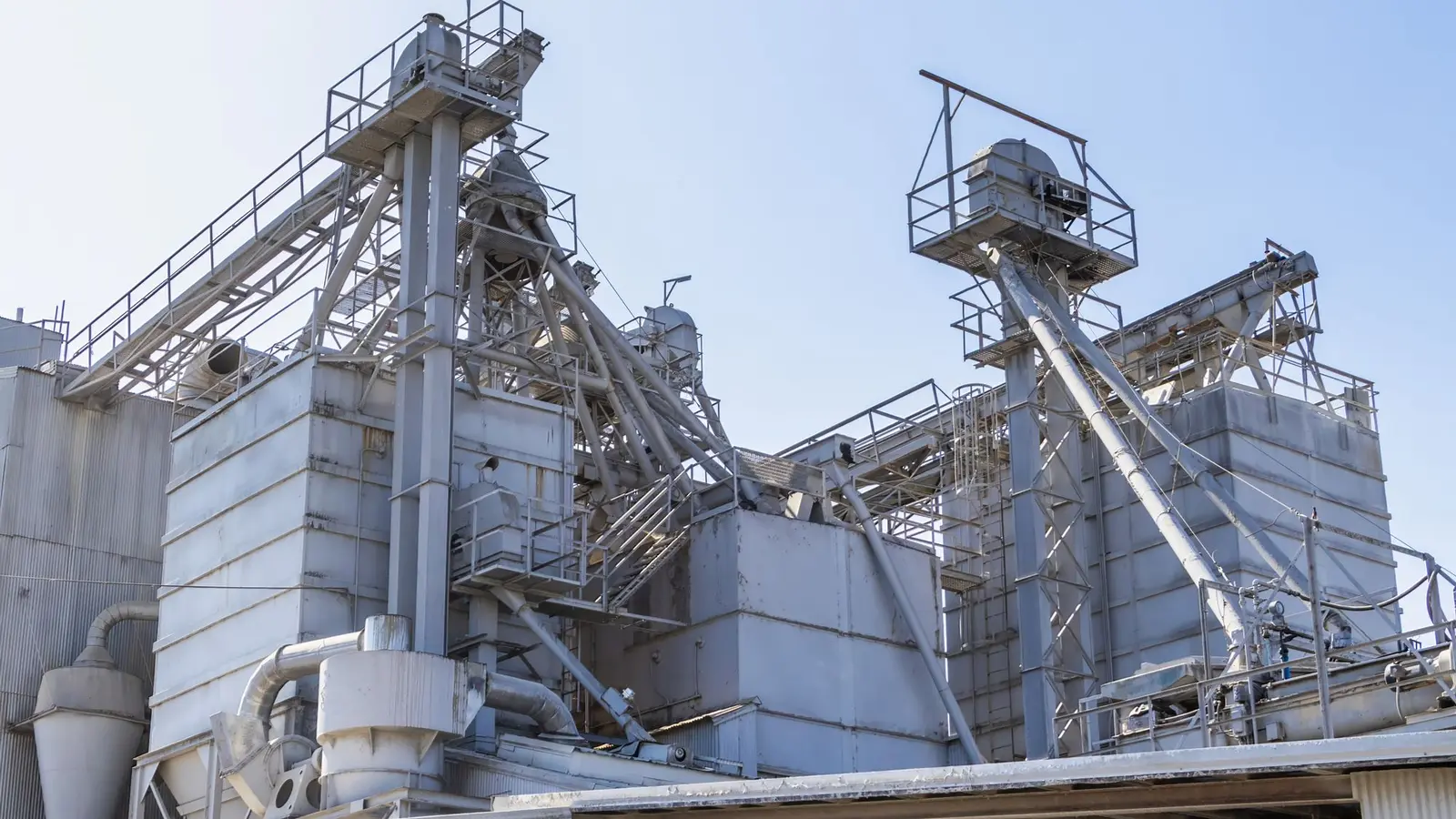 Industrial cement plant structures with elevated conveying equipment