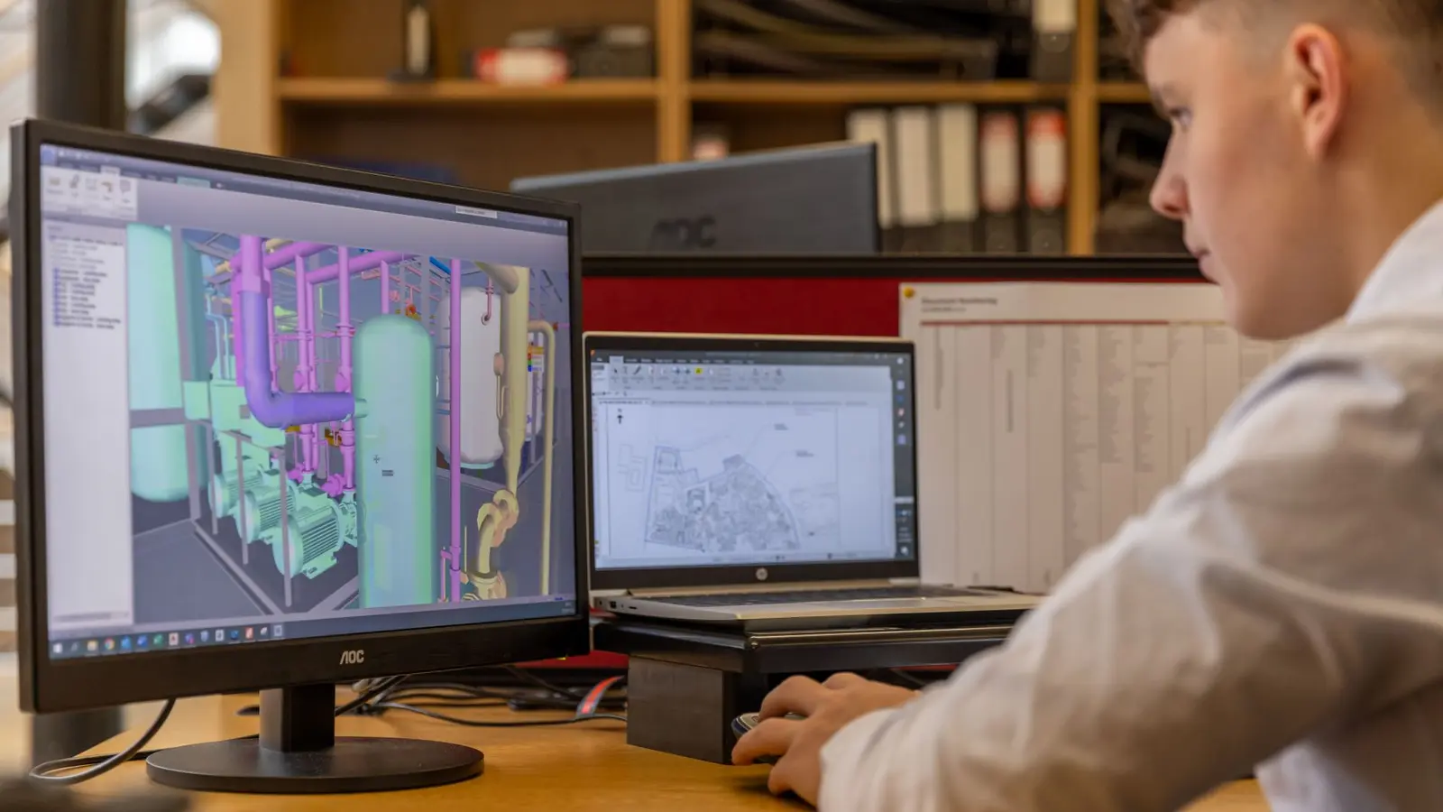 Engineer reviewing equipment design data on CAD workstations